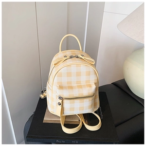 Détail d'un petit sac à dos à carreaux jaunes et blancs avec poignée et poche zippée