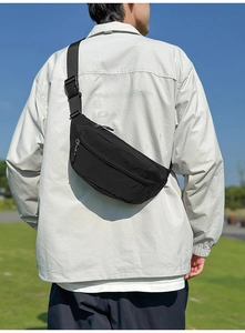 Outdoor close-up of a black waterproof nylon crossbody bag with adjustable strap