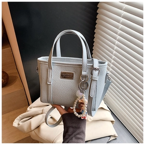 Detail der hellblauen Leder-Eimertasche mit Lychee-Muster und silbernem Logo-Schild