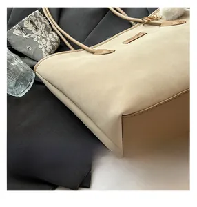 Detail of dual-material tote bag with beige suede, brown leather and fluffy charm