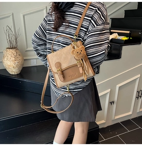 Detail of vintage brown contrast backpack with buckle straps and plush bear charm