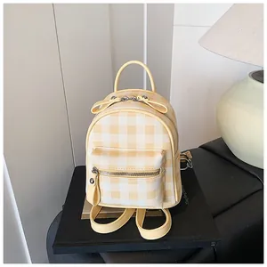 Vue détaillée du mini sac à dos à carreaux jaunes avec poche zippée dans un cadre épuré