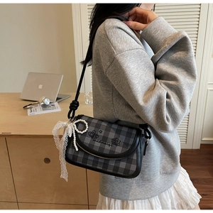 Detail of grey plaid crossbody bag with lace bow, pearl chain and stylish heart print