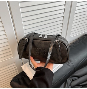 Close-up of black matte leather pillow bag with debossed lettering and adjustable silver buckle