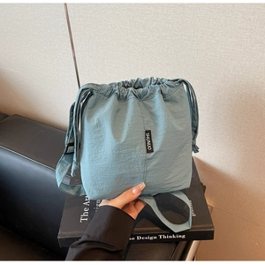 Detail of blue drawstring bucket bag with adjustable strap and textured fabric