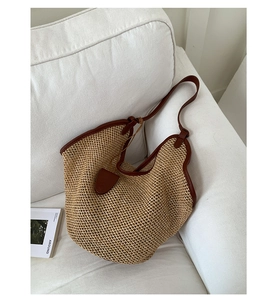Detail of woven straw bucket bag showing honeycomb texture and brown leather straps