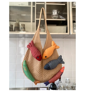 Close-up of brown knit tote bag featuring colorful fish-shaped stuffed fabric charms