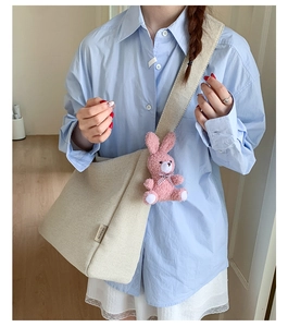 Detail of cream canvas tote bag featuring a cute pink plush bunny pendant and wide strap