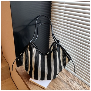 Detail of striped mesh tote bag showing woven texture and black leather shoulder straps