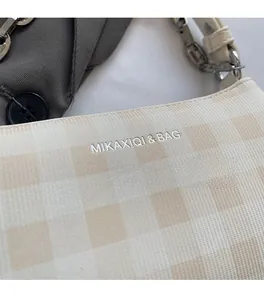 Close-up of checkered shoulder bag with silver logo and metal chain detail
