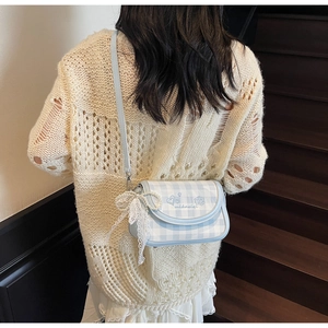 Detail view of light blue checkered crossbody bag with lace bow and cloud embroidery
