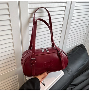 Detail of burgundy leather shoulder bag with adjustable strap and silver-tone hardware