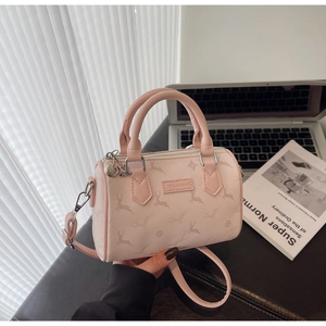 Detail of pink Boston bag with elk pattern print, hand-held near a laptop