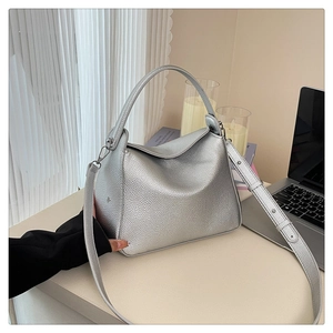 Detail of silver lychee-textured bucket bag with top handle and adjustable shoulder strap