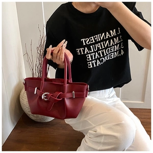 Détail du sac seau en cuir mat bordeaux avec boucle décorative et doubles poignées