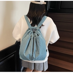 Back view of a light blue drawstring backpack with waterproof fabric on a female model