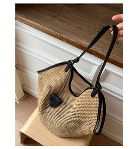 Macro detail of hand-woven straw tote with black leather trim and reinforced straps