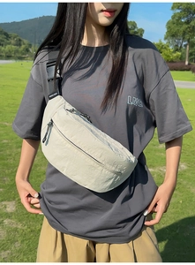 Detail of adjustable strap and front pocket on beige nylon crossbody fanny pack