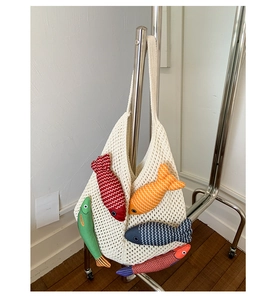 Close-up of knit tote bag featuring colorful hanging fish charms and mesh texture