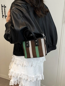 Sac seau tissé à rayures vertes et marron porté par un mannequin en veste de cuir élégante