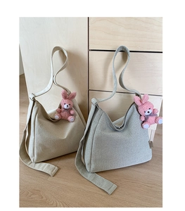Detail of beige and sage green canvas tote bags with cute pink plush bunny pendants