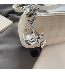 Close-up of a silver balloon dog pendant on a creamy checkered pattern chain shoulder bag