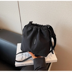 Detail view of black drawstring bucket bag with Shunuo brand tag and textured nylon fabric