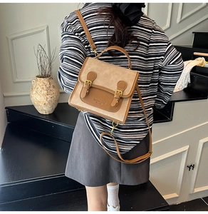 Close-up of retro khaki and brown contrast handbag featuring vintage metal buckle straps