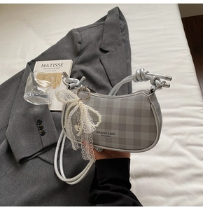 Détail du sac à carreaux gris avec breloque nœud en dentelle perlée et poignée argentée