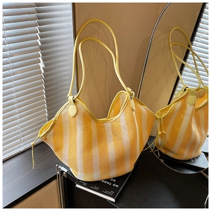 Detail of yellow and white striped mesh tote bag with leather handles and drawstring