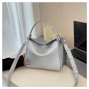 Macro shot of silver lychee grain leather texture and metallic hardware on the handbag