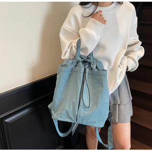 Detail of light blue drawstring backpack showing dual front pockets and soft nylon fabric