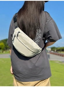 Beige waterproof crossbody fanny pack for men and women worn in an outdoor park setting