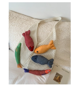 Detail of crochet tote bag featuring five colorful knit fish charms on beige mesh fabric