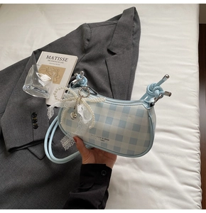 Détail d'un sac à main à carreaux bleu clair avec nœud en perles et lettrage de marque