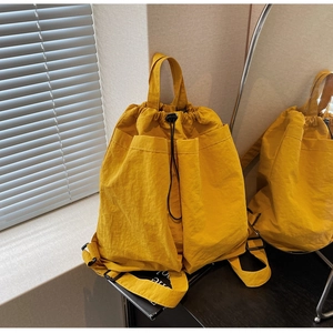 Detail of bright yellow drawstring backpack with large front pockets and carry handle