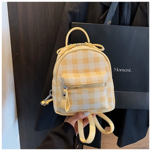 Gros plan détaillé du mini sac à dos à carreaux jaune et blanc avec fermetures argentées