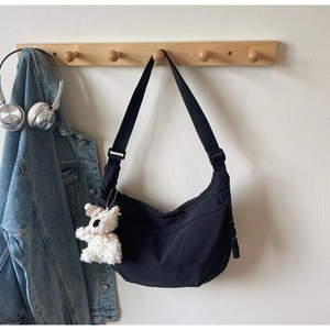 Detail of black dumpling crossbody bag with adjustable strap and cute plush puppy charm