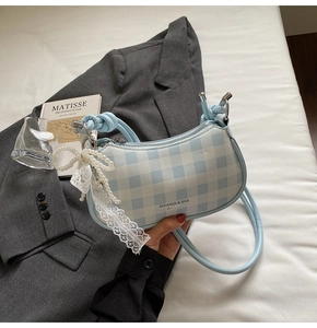 Détail du sac croissant à damier bleu clair avec breloque perle et nœud en dentelle