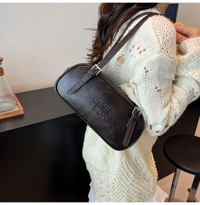 Detail of vintage brown leather underarm bag with embossed texture and metal buckle