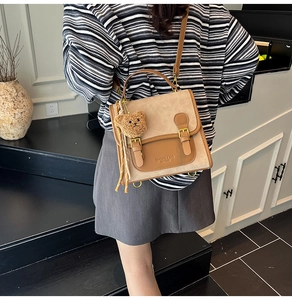 Detail of vintage beige frosted crossbody bag with leather trim and bear pendant charm
