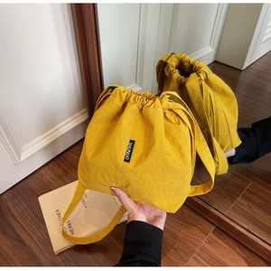 Detail of bright yellow drawstring bucket bag showing textured nylon fabric and brand tag