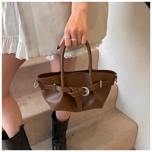 Détail d'un sac seau plissé en cuir marron avec ceinture décorative et boucle argentée
