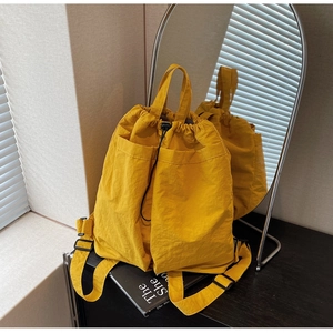 Detail of a bright yellow nylon drawstring backpack with crinkled texture and outer pockets