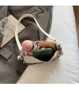 Detail view of cream shoulder bag interior holding a phone, umbrella, and wallet