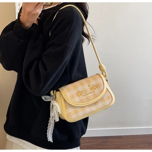 Detail of yellow checkered bag with heart embroidery and pearl lace charm