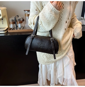 Detail of vintage caramel cylinder shoulder bag with embossed texture and adjustable straps