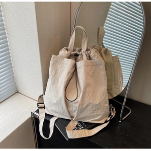 Close-up of light beige drawstring backpack featuring pleated texture and dual straps