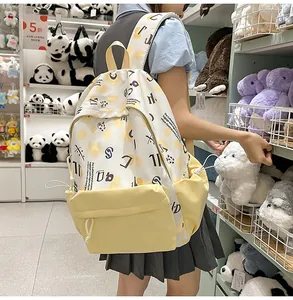 Dettaglio di uno zaino in tela beige con stampa a pois gialli e tasche laterali con coulisse