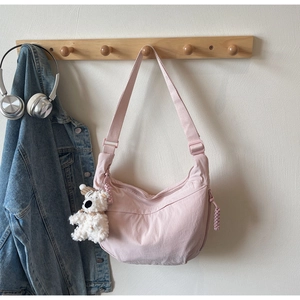 Detailed view of pink crescent dumpling bag with a cute plush bear pendant accessory